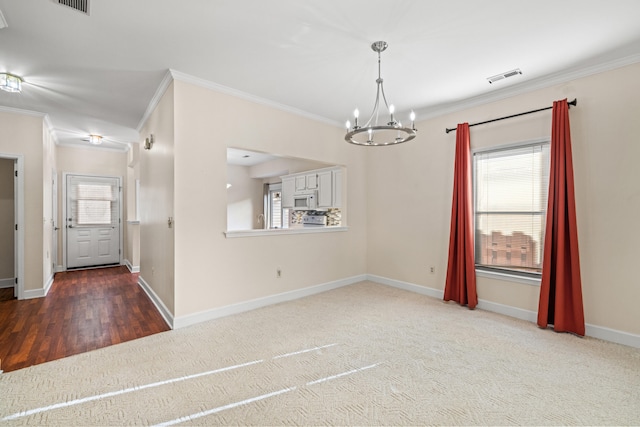 empty room with dark carpet, ornamental molding, and a notable chandelier