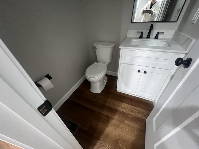 bathroom with toilet, vanity, and hardwood / wood-style flooring