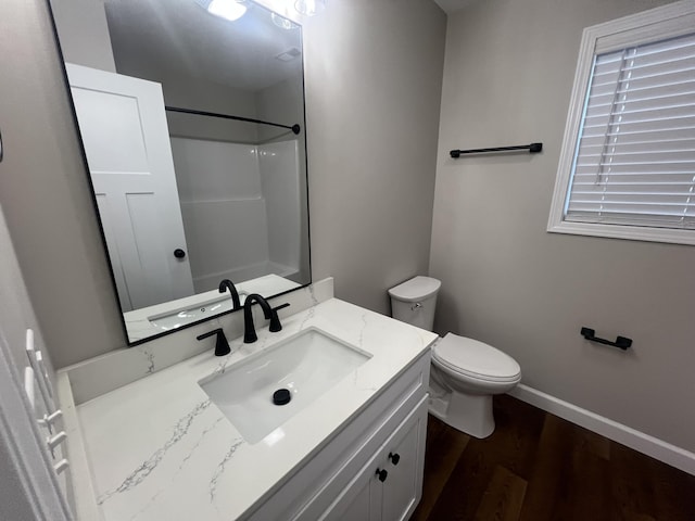 bathroom featuring wood-type flooring, vanity, toilet, and walk in shower