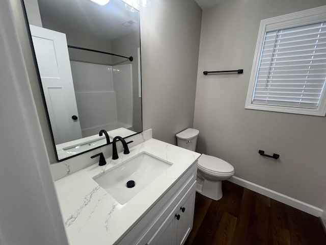 bathroom with walk in shower, hardwood / wood-style floors, vanity, and toilet