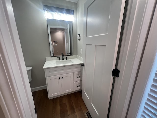 bathroom with toilet, vanity, and hardwood / wood-style flooring