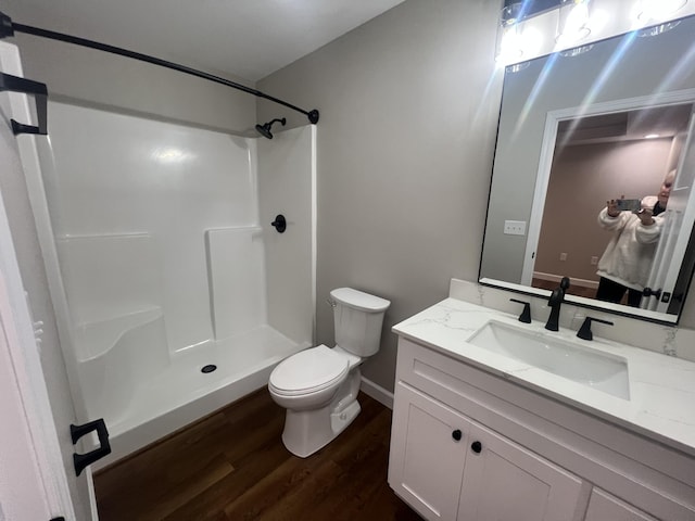 bathroom with hardwood / wood-style flooring, toilet, vanity, and walk in shower