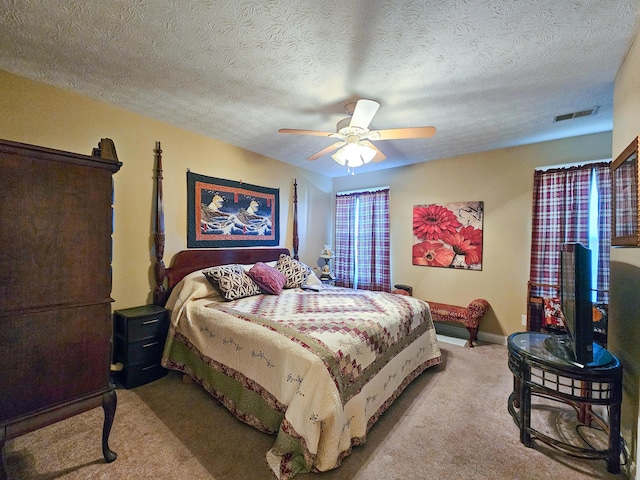 carpeted bedroom featuring ceiling fan and a textured ceiling