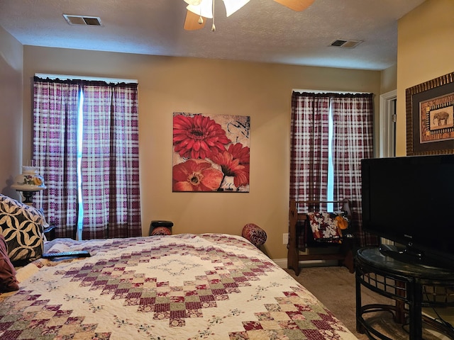 carpeted bedroom featuring ceiling fan and a textured ceiling