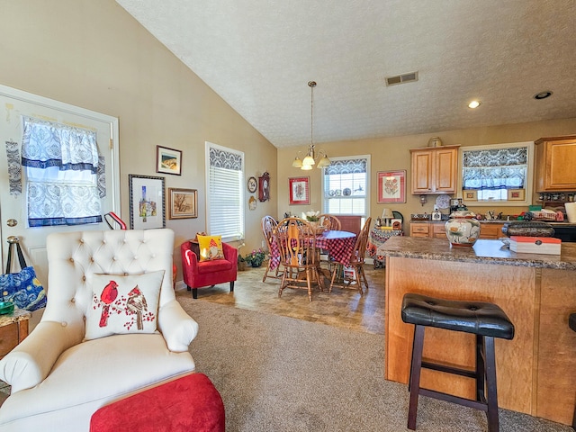 interior space featuring hanging light fixtures, an inviting chandelier, a textured ceiling, vaulted ceiling, and a breakfast bar area