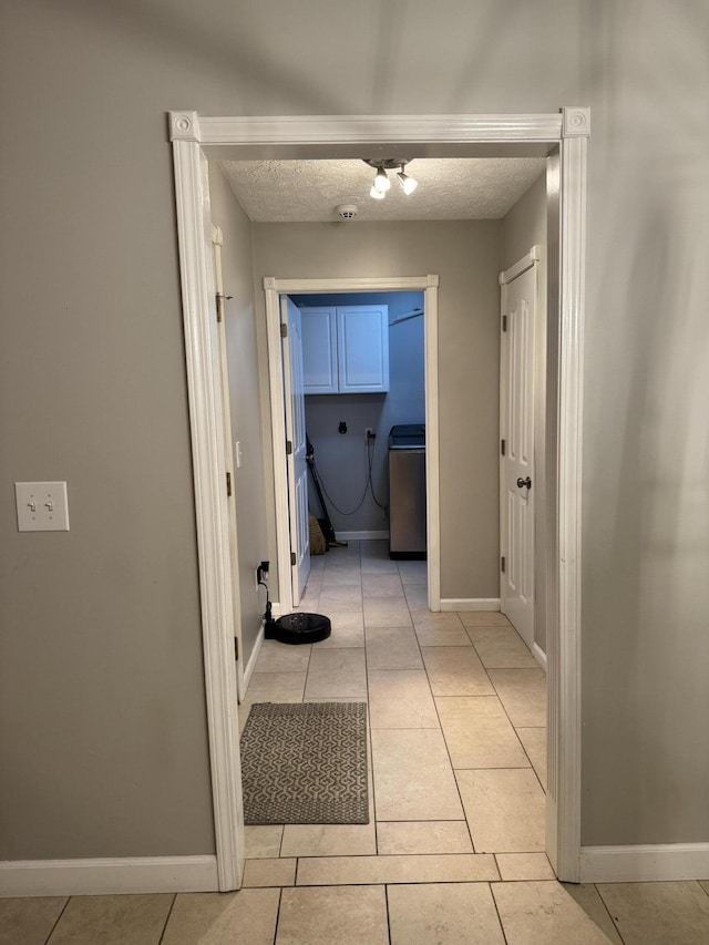 corridor with a textured ceiling and light tile patterned flooring