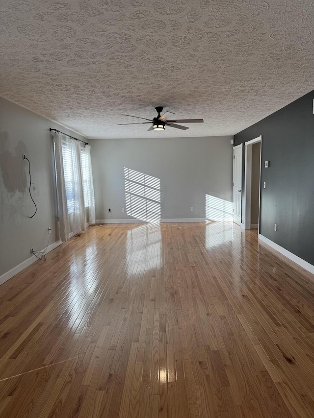 empty room with ceiling fan, light hardwood / wood-style floors, and a textured ceiling