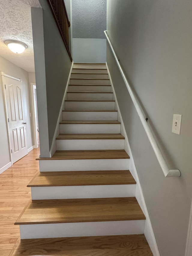 stairs with hardwood / wood-style floors and a textured ceiling