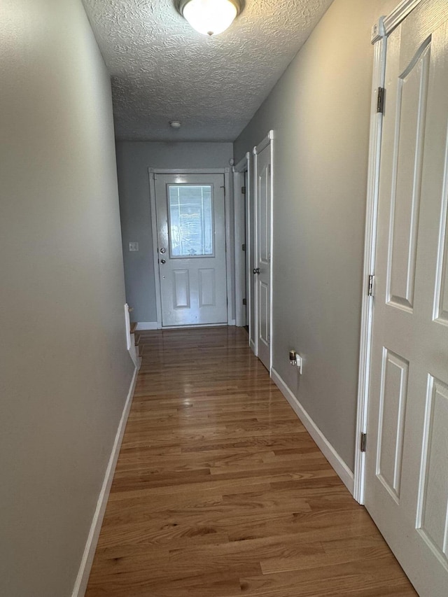 hallway with hardwood / wood-style floors and a textured ceiling