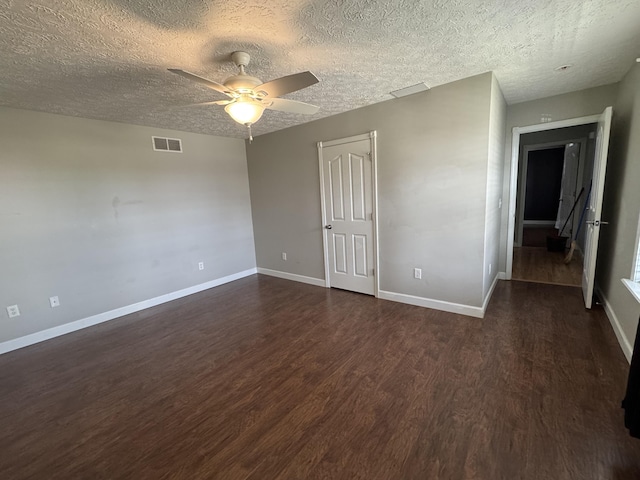 empty room featuring ceiling fan, dark hardwood / wood-style floors, and a textured ceiling