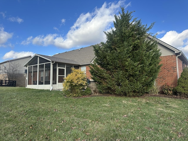 back of house featuring a lawn and a sunroom