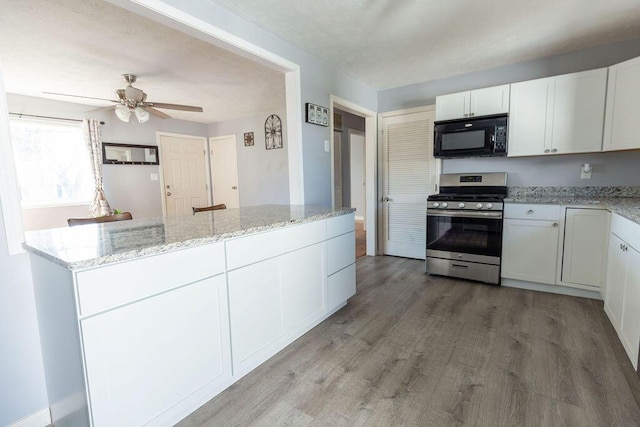 kitchen featuring ceiling fan, light stone countertops, stainless steel range, light hardwood / wood-style floors, and white cabinetry