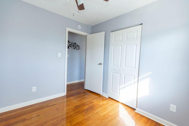 unfurnished bedroom with ceiling fan, a closet, and wood-type flooring