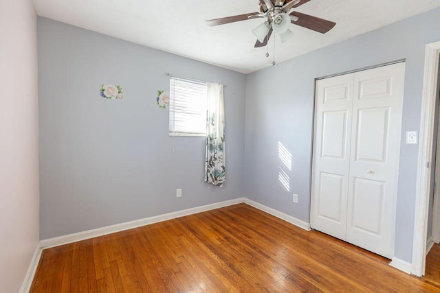 unfurnished bedroom featuring ceiling fan, a closet, and hardwood / wood-style flooring