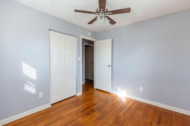 unfurnished bedroom featuring ceiling fan, a closet, and wood-type flooring