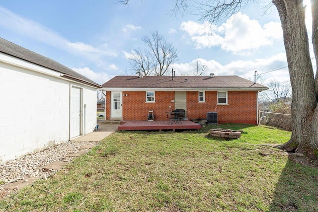 back of property with a fire pit, a yard, a wooden deck, and central AC