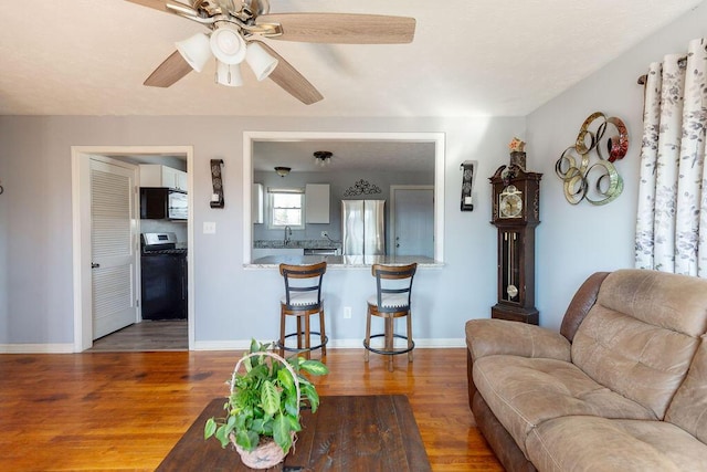 living room with hardwood / wood-style flooring, ceiling fan, and sink