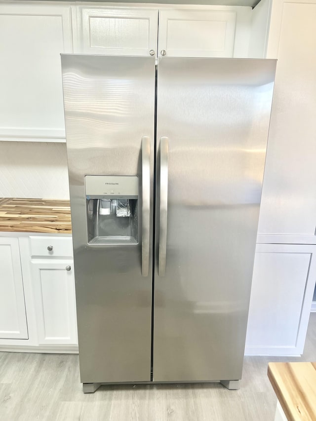 kitchen with butcher block countertops, white cabinetry, light wood-type flooring, and stainless steel fridge with ice dispenser