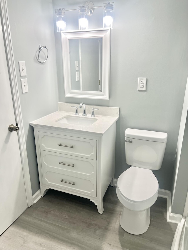 bathroom with toilet, vanity, and hardwood / wood-style flooring