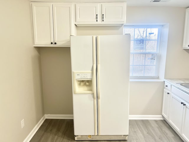 kitchen featuring white refrigerator with ice dispenser, light hardwood / wood-style floors, white cabinetry, and sink