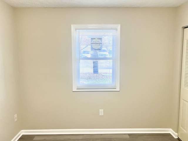 unfurnished room featuring plenty of natural light and dark hardwood / wood-style floors