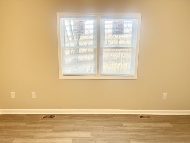 empty room with plenty of natural light and light hardwood / wood-style flooring