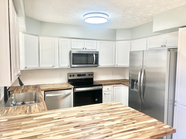 kitchen featuring white cabinetry, sink, wooden counters, a textured ceiling, and appliances with stainless steel finishes