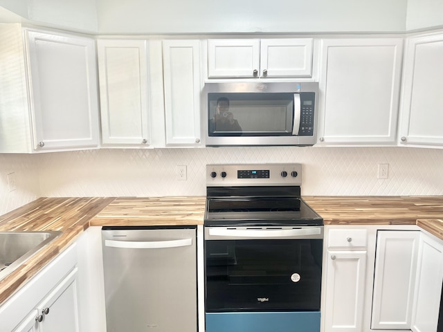 kitchen featuring wooden counters, stainless steel appliances, white cabinets, and tasteful backsplash