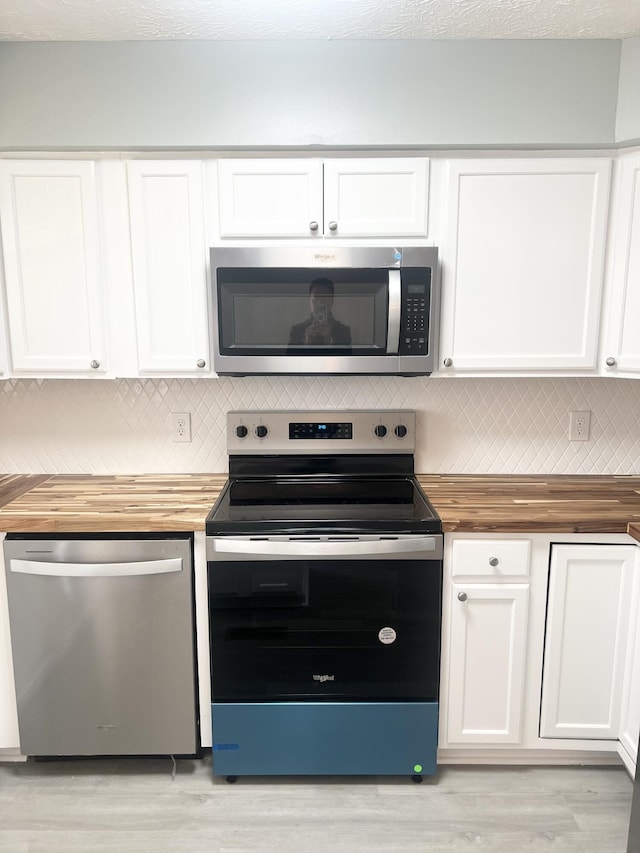 kitchen with white cabinetry, light hardwood / wood-style flooring, stainless steel appliances, and wood counters