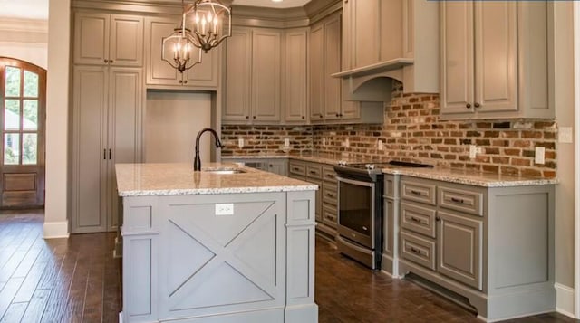 kitchen with pendant lighting, stainless steel range with electric cooktop, a kitchen island with sink, sink, and light stone counters