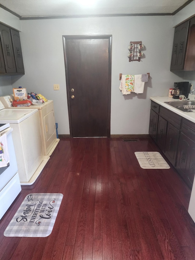 laundry room with dark hardwood / wood-style flooring, crown molding, washer and clothes dryer, and sink