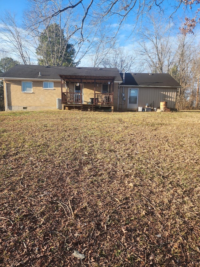 back of property with a deck, central air condition unit, and a yard