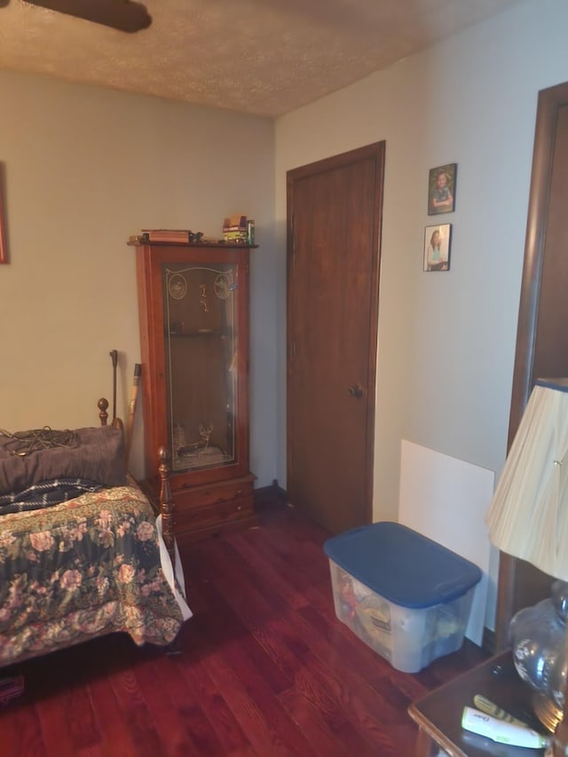 bedroom with dark hardwood / wood-style floors, ceiling fan, and a textured ceiling