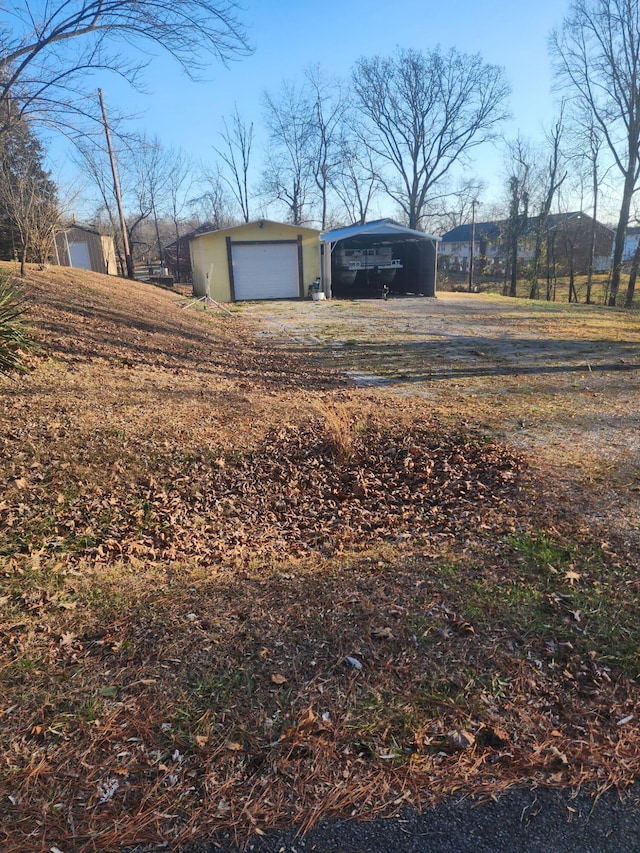 view of yard with a garage, a carport, and an outdoor structure