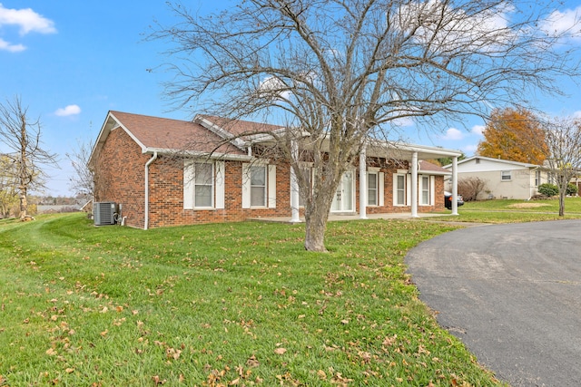 ranch-style house featuring central AC unit and a front lawn