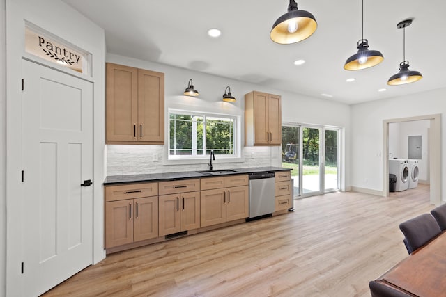 kitchen with sink, hanging light fixtures, stainless steel dishwasher, washing machine and dryer, and plenty of natural light