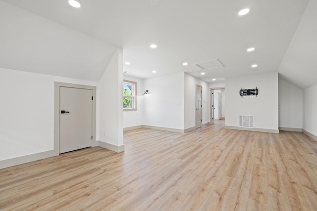 bonus room with light wood-type flooring and vaulted ceiling