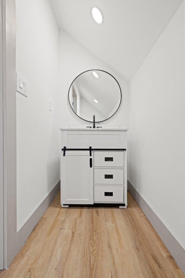 bathroom with hardwood / wood-style floors, vanity, and vaulted ceiling