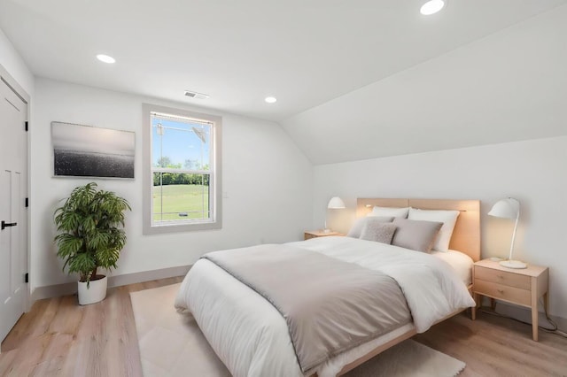 bedroom with light hardwood / wood-style floors and lofted ceiling