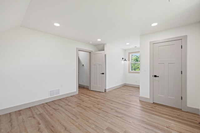 unfurnished room featuring light wood-type flooring and lofted ceiling