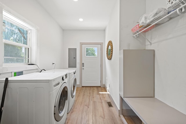 clothes washing area featuring washer and clothes dryer, electric panel, and light hardwood / wood-style flooring