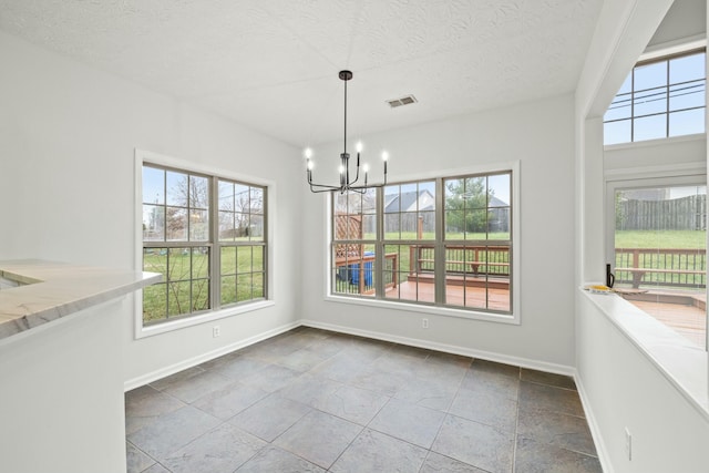 unfurnished dining area featuring a textured ceiling and an inviting chandelier