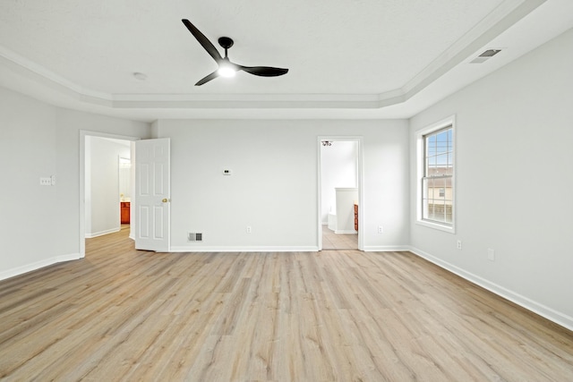 unfurnished bedroom with ceiling fan, light hardwood / wood-style floors, connected bathroom, and a tray ceiling