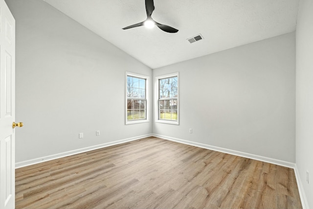 spare room featuring ceiling fan, lofted ceiling, and light hardwood / wood-style flooring