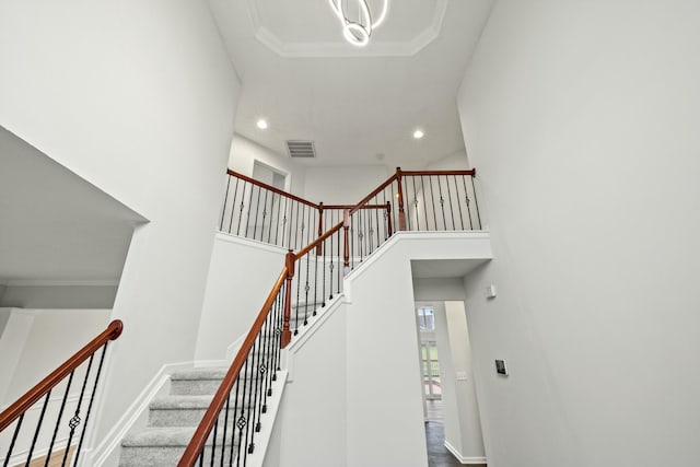 stairway featuring ornamental molding and a towering ceiling