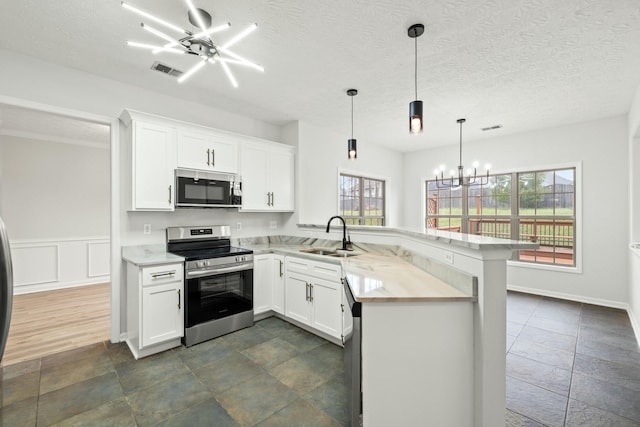 kitchen featuring kitchen peninsula, appliances with stainless steel finishes, sink, pendant lighting, and white cabinets