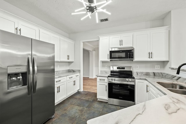 kitchen with white cabinetry, sink, stainless steel appliances, and light stone counters