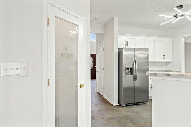 kitchen with a textured ceiling, white cabinets, and stainless steel refrigerator with ice dispenser