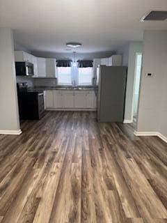 unfurnished living room featuring dark wood-type flooring and sink