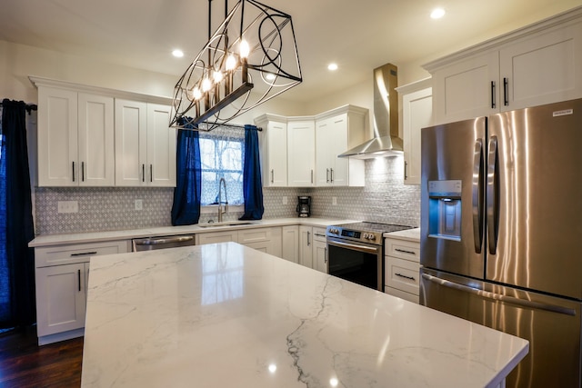 kitchen with sink, wall chimney exhaust hood, light stone countertops, appliances with stainless steel finishes, and decorative light fixtures